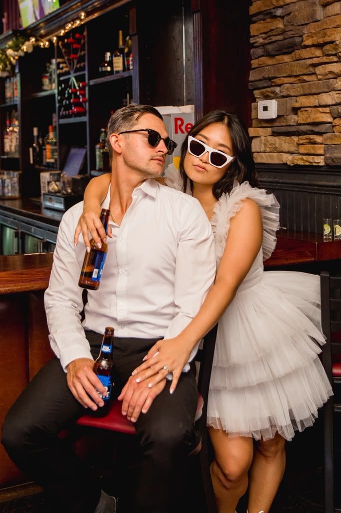 Playful couple in sunglasses posing at a cozy bar
