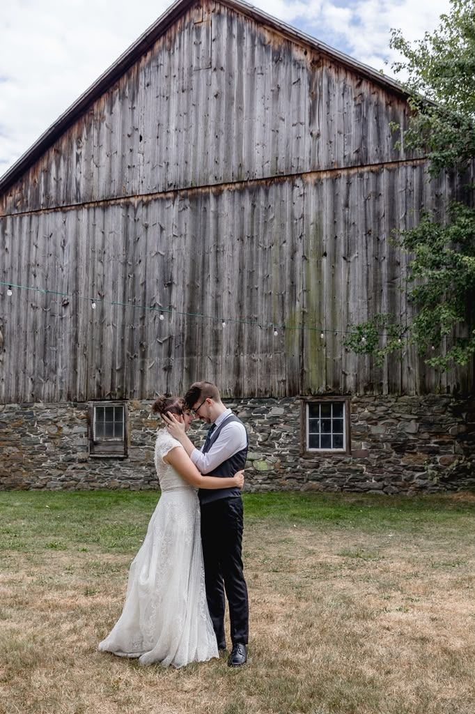 Couple embracing in front of a weathered wooden barn