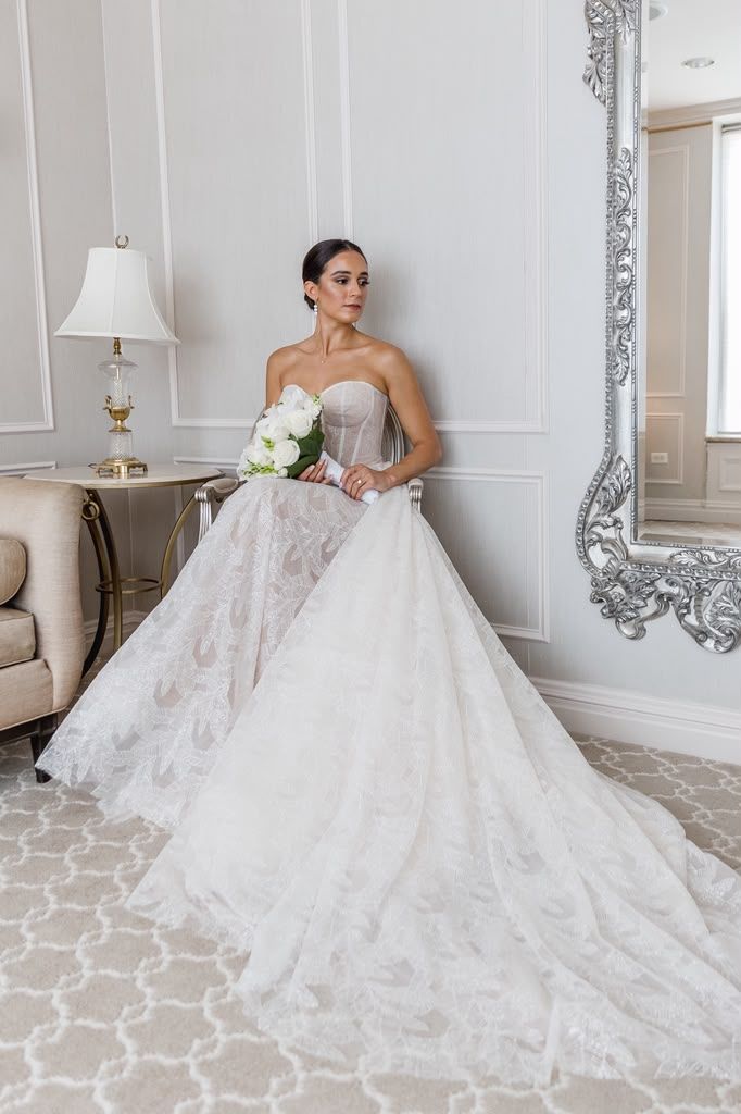 Bride seated in an elegant white parlor with a voluminous gown