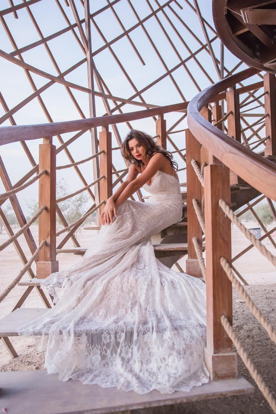 Bride in a lace gown posed on a sculptural spiral staircase