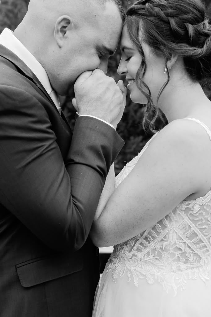 Black and white close-up of a groom kissing his bride's hand