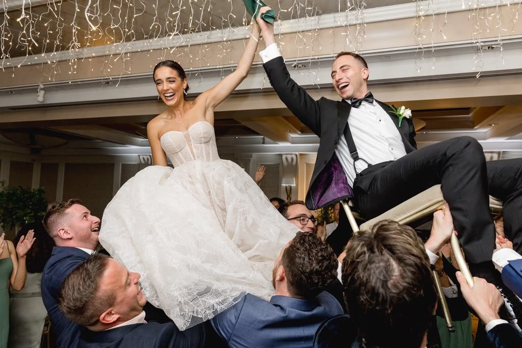 Bride and groom lifted on chairs during a reception celebration