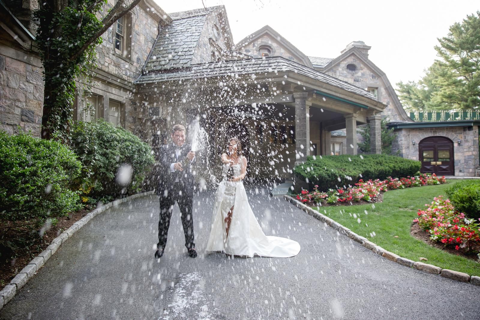 Couple showered in confetti outside a stone estate