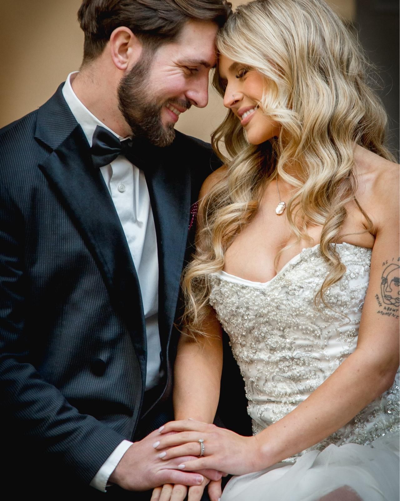 Close-up of bride and groom touching foreheads and holding hands