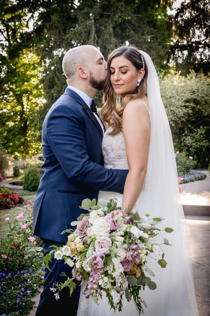 Couple in a sunlit garden holding a pastel wildflower bouquet