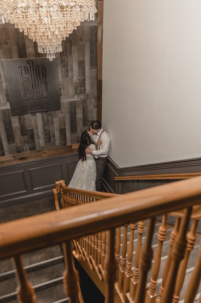 Couple embracing below a crystal chandelier in a loft stairwell