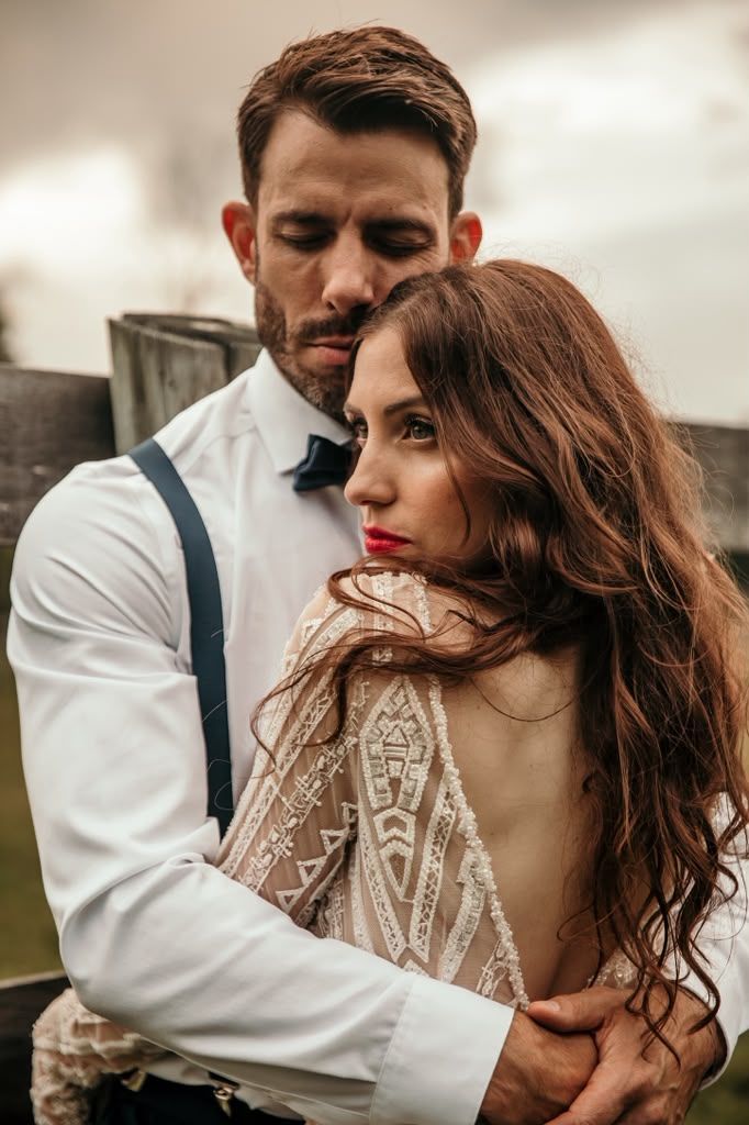 Moody portrait of a groom embracing his bride from behind