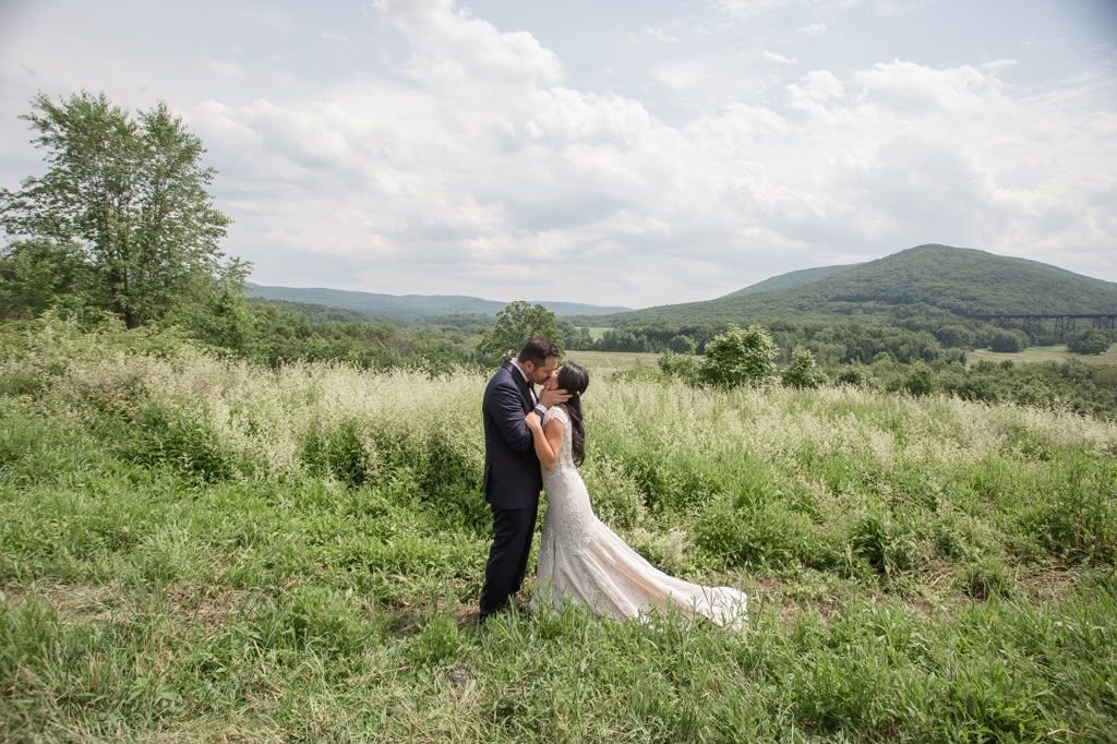Couple kissing in a mountain meadow under a wide sky