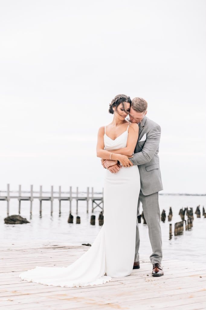 Couple embracing on a waterfront pier on an overcast day