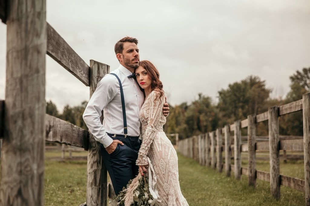 Couple posing together by a rustic wooden fence